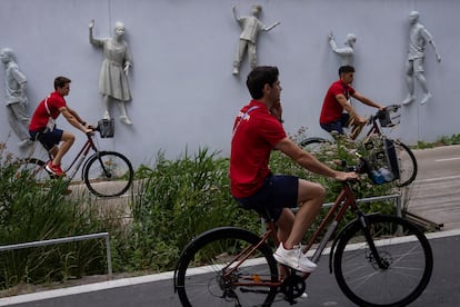 Tres atletas españoles se mueven en bicicleta por la Villa Olímpica.
