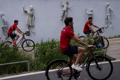 Tres atletas españoles se mueven en bicicleta por la Villa Olímpica.