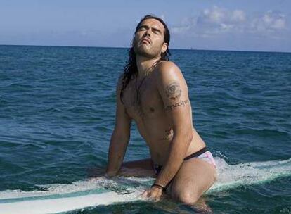 El artista Russell Brand, sobre una tabla de surf.