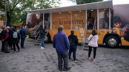 Gente hace cola para entrar en un autobús que informa sobre el Ingreso Mínimo Vital, en junio de 2023 en Parla (Madrid).