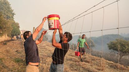 Residentes locales llevan agua para apagar las llamas en Alto do Alvide, cerca de Cascais (Portugal), este martes. 
