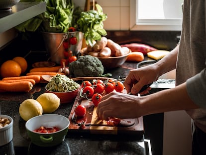 Un hombre prepara una comida vegana con verduras y frutas.