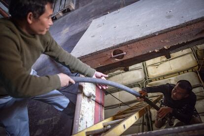 El mecánico Than Htike (izquierda) ayuda al contramaestre Nyo Tun Lwin a sacar una manguera de la bodega.