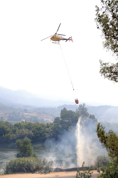 Un helicóptero de los bomberos lanza agua sobre el incendio forestal en Xerta (Tarragona), este martes.
