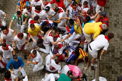 Decenas de corredores se apartan al paso de uno de los toros de Victoriano del Ríon en el tercer encierro de los Sanfermines este martes.
