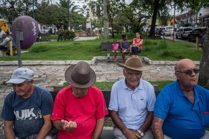 Cuatro hombres descansan en la plaza central de Eldorado delante de dos mujeres y una niña.