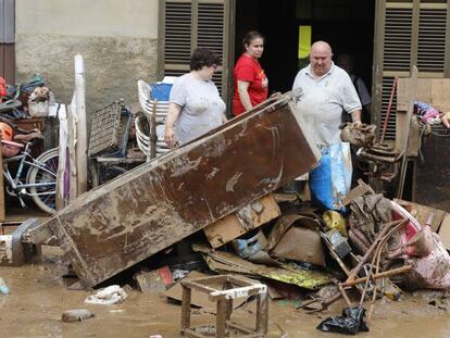 Veïns de Sant Llorenç des Cardassar netegen casa seva després del pas de la torrentada per la localitat.