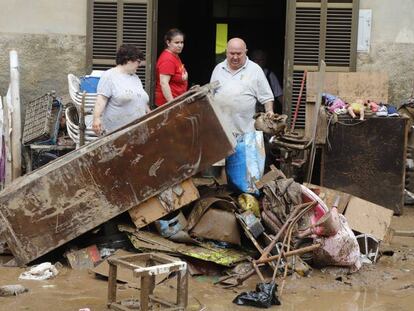 Veïns de Sant Llorenç des Cardassar netegen casa seva després del pas de la torrentada per la localitat.