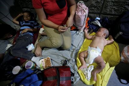 Una familia duerme en el suelo durante la caravana hacia Estados Unidos, en San Pedro Sula, el 13 de octubre de 2018. 