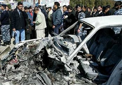 Policías palestinos inspeccionan el coche atacado, que ha quedado reducido a un amasijo de hierros.