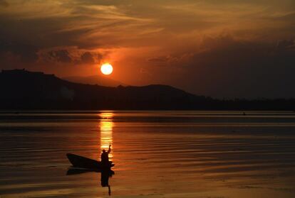 Un barquero de Cachemira rema en el lago Del durante una puesta de sol en Srinagar (India).