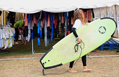 Una mujer, asistente al festival, recoge su tabla antes de comenzar las clases de surf.