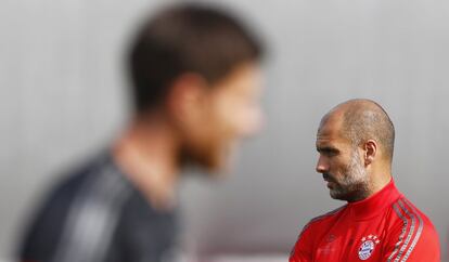 En primer plano, desenfocado, Xabi Alonso. Al fondo, Guardiola.