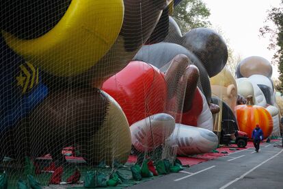 Un trabajador camina a lo largo de una fila de globos gigantes, ya inflados, que esperan debajo de redes sostenidas con pesas la llegada del Día de Acción de Gracias.
