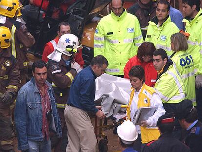 Uno de los fallecidos en el derrumbe es trasladado por bomberos y miembros del 061.