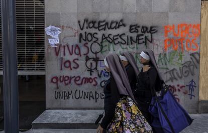 Tres mujeres caminan frente a uno de los muros que fue pintado durante las protestas feministas en Ciudad de México.