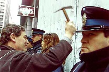 Un manifestante da martillazos en la fachada de un banco de Buenos Aires.