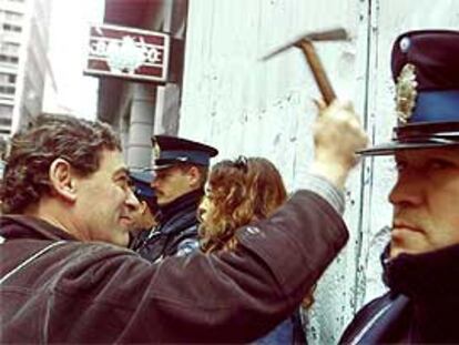 Un manifestante da martillazos en la fachada de un banco de Buenos Aires.