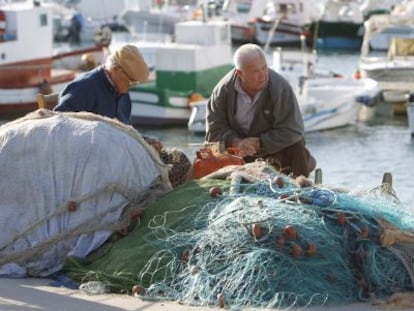 Dos hombres reparan unas redes en el puerto de Barbate.