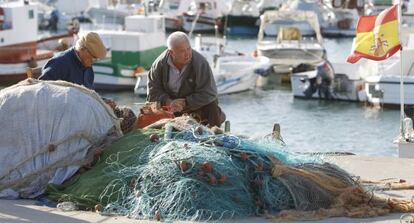 Dos hombres reparan unas redes en el puerto de Barbate.