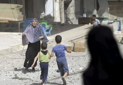 Una mujer corre a por sus hijos tras un bombardeo en Idlib, Siria.