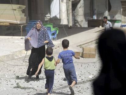 Mulher corre para pegar seus filhos após um bombardeio em Idlib, na Síria.