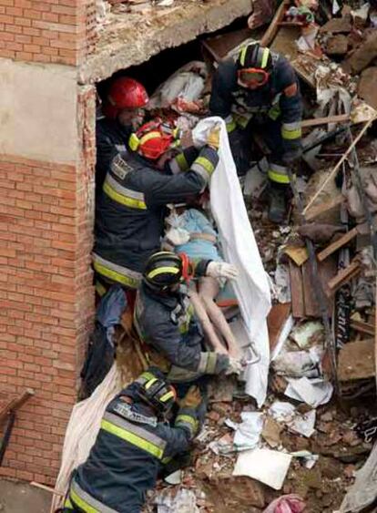 Los bomberos rescatan uno de los cadáveres de entre los escombros del edificio.