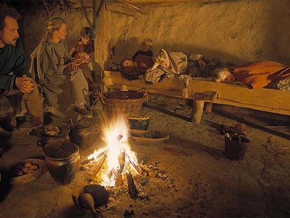 Una familia reunida alrededor de la hoguera en una de las chozas del pueblo de la edad del hierro en el Lejre Experimental Center.