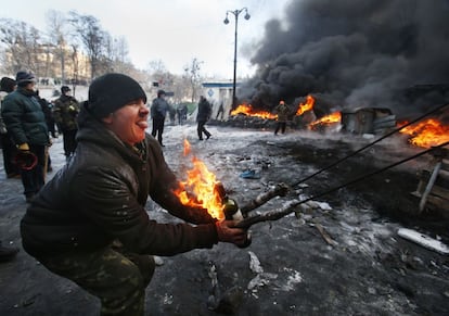 Un manifestante opositor al gobierno ucranio utiliza un gran tirachinas para lanzar un cóctel molotov contra la policía en el centro de Kiev, Ucrania. El humo negro procedente de la quema de neumáticos estuvo presente por distintas partes del centro de Kiev.