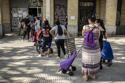 Un grupo de personas hace cola en el banco de alimentos Gran Avenida 24, en el barrio de Orcasitas, Madrid.