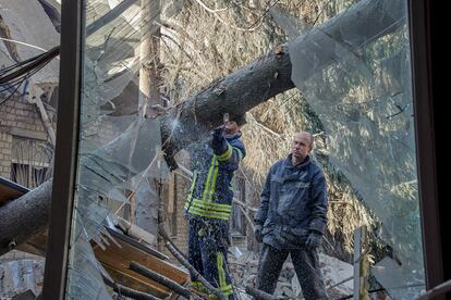 Dos rescatistas ucranios limpian los escombros en una escuela después de un bombardeo en una zona residencial de Járkov, Ucrania, este lunes.
