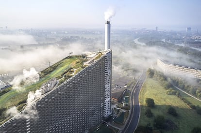 Bajo el manto verde de la foto —una pista de esquí sintética de 370 metros de longitud— se encuentra la planta de producción de energía más eficiente, limpia y divertida de Dinamarca. Los dos hornos de Amager Bakke, a orillas del estrecho de Oresund, en Copenhague, incineran entre 50 y 70 toneladas de basura cada hora que se transforman en electricidad y calefacción urbana para los hogares de la capital danesa. Además, no generan malos olores —el aire del silo de desechos se aspira y se utiliza para regular la temperatura de combustión— y el humo que exhalan sus chimeneas está libre de toxinas, gracias a un sistema de depuración con diversos filtros y un catalizador que elimina el óxido de nitrógeno. Por ello su inclinada azotea acoge desde hace un año la Copenhill (<a href="https://www.copenhill.dk/en/" target="_blank">copenhill.dk</a>), una colina artificial que ofrece descensos de esquí y snowboard por cuatro pistas de diferente dificultad e inclinación, senderos para caminar, un mirador a 82 metros de altura y un rocódromo de 80 metros que asciende por la fachada.