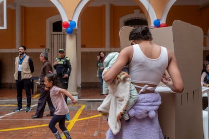 Una mujer con un bebé vota en el centro de votación del Colegio Mayor de San Bartolomé.