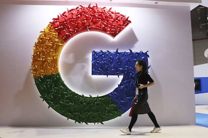 Una mujer camina delante del logo de Google.