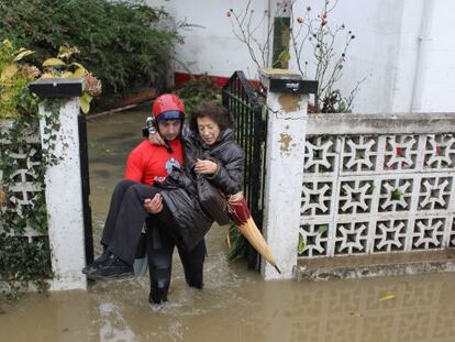 Un bombero lleva en brazos a una mujer para ayudarla a salir de su casa tras las inundaciones que en noviembre de 2011 asolaron los barrios donostiarras de Txomin y Martutene.