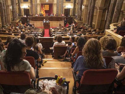 Una dona amb el seu fill segueix el ple especial al Parlament en defensa del moviment feminista.