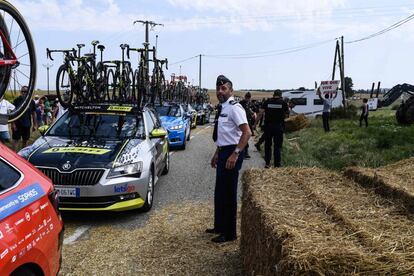 Un oficial observa cómo los coches de los ciclistas avanzan por la carretera tras haber despejado la zona.