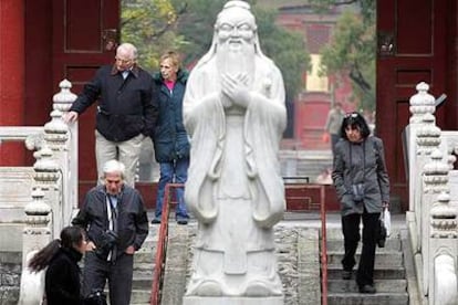 Unos turistas pasean junto a una estatua de Confucio en Pekín.
