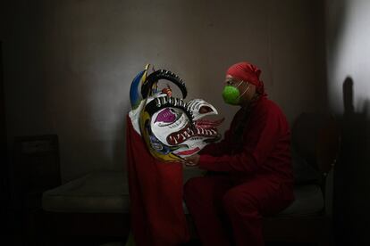 Un hombre sostiene su máscara de demonio antes de prepararse para participar en las celebraciones del Corpus Christi de San Francisco de Yare, Venezuela.