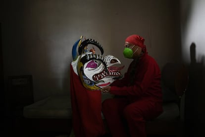 Un hombre sostiene su máscara de demonio antes de prepararse para participar en las celebraciones del Corpus Christi de San Francisco de Yare, Venezuela.