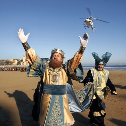 El rey Gaspar saluda a los niños tras descender del helicoptero que les transportó hasta la playa de San Lorenzo de Gijón.