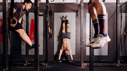 Tres hombres practican distintos ejercicios de 'crossfit' en el box Condal CrossFit Gràcia, en Barcelona.