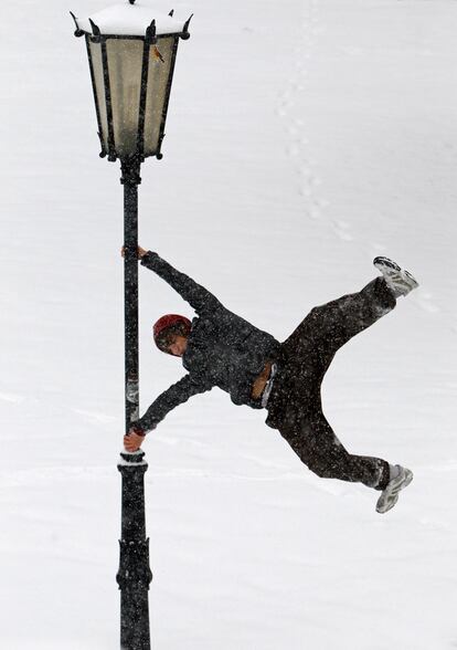 Un joven gira entorno a una farola en un parque de Viena, totalmente cubierto de nieve.