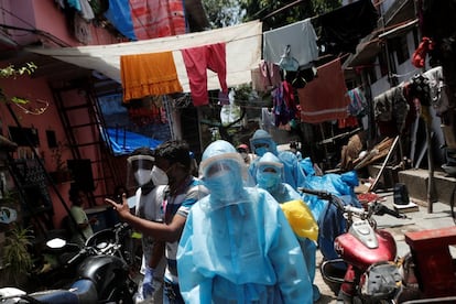 Sanitarios con equipo de protección contra el coronavirus caminan por un barrio pobre en Dharavi, para controlar a los residentes durante un encierro para frenar la propagación de la enfermedad en Mumbai (India). Este país comenzará mañana oficialmente la primera fase de su proceso de desescalada para poner fin al mayor y más largo confinamiento de su historia.