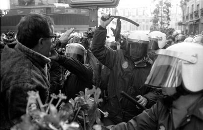 Un agente antidisturbios de la policía a punto de golpear con la porra a unos huelguistas durante la jornada de paro en Madrid.