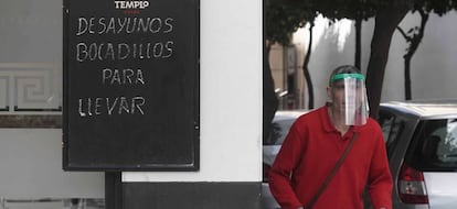 Un trabajador protegido con una máscara reparte en un bar de Córdoba.