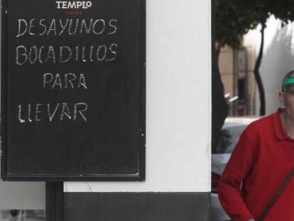 Un trabajador protegido con una máscara reparte en un bar de Córdoba.