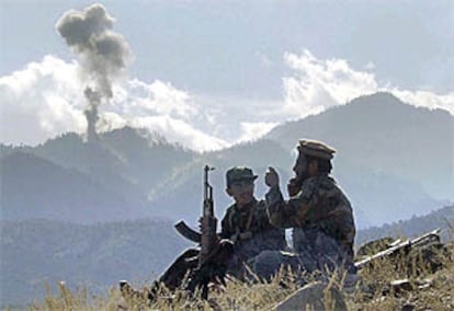 Dos <i>muyahidin</i> charlan mientras observan el humo de las bombas lanzadas sobre Tora Bora.