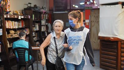 Una voluntaria de la Universidad de Buenos Aires acompaña a una mujer mayor durante una jornada de la campaña de vacunación en la capital de Argentina.