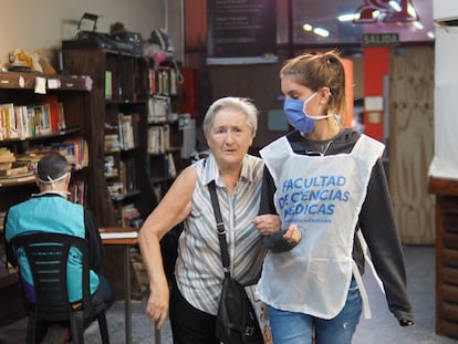 Una voluntaria de la Universidad de Buenos Aires acompaña a una mujer mayor durante una jornada de la campaña de vacunación en la capital de Argentina.
